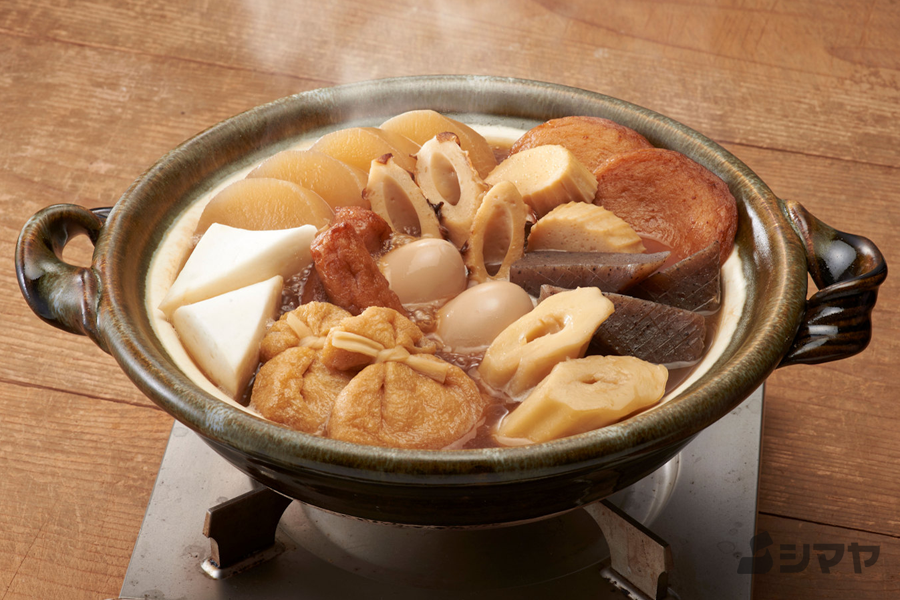A traditional Japanese hot pot “oden” served in a clay pot, filled with daikon radish, eggs, fish cakes, and konjac.